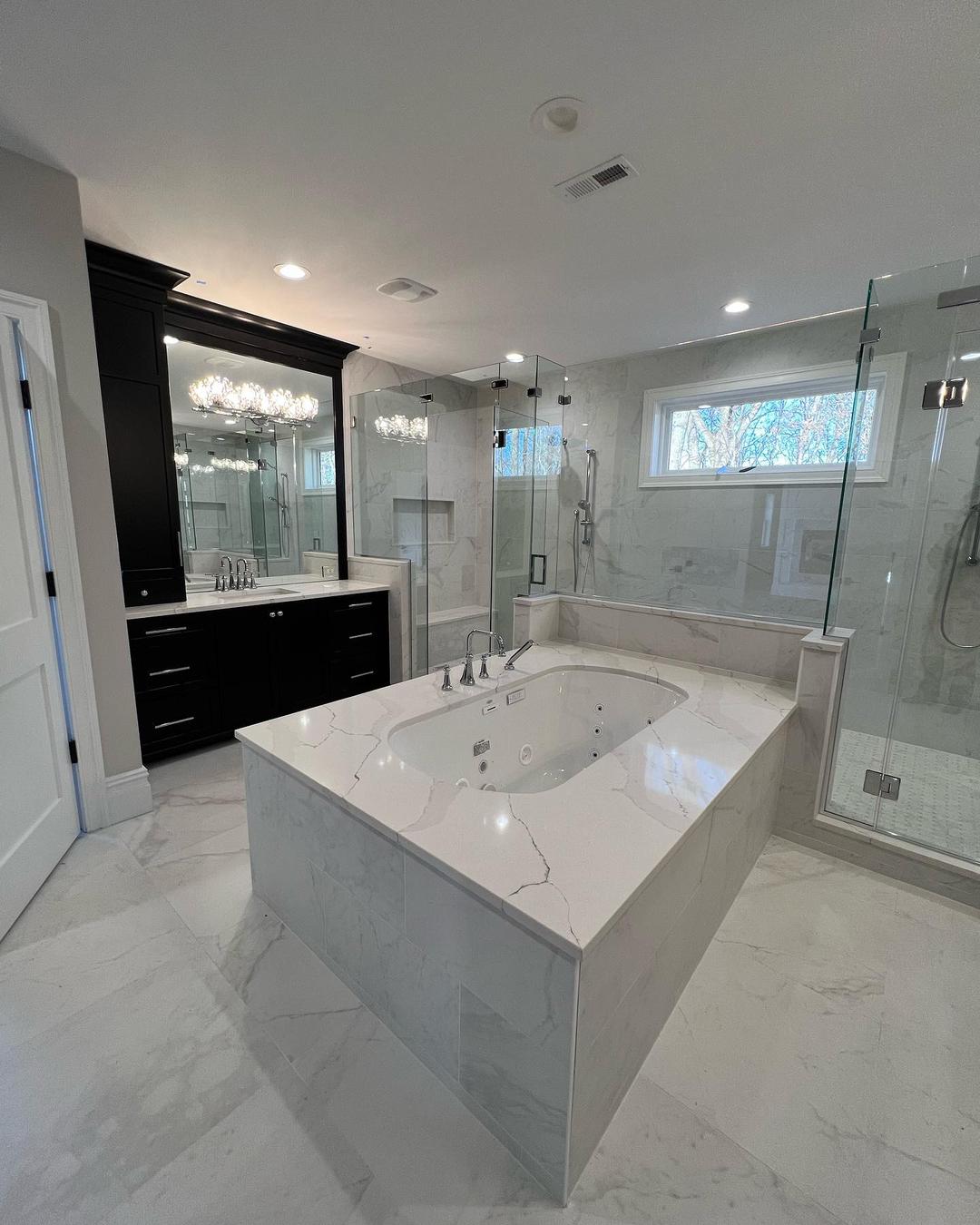 Large tub in marble. Two showers and a vanity in the background.