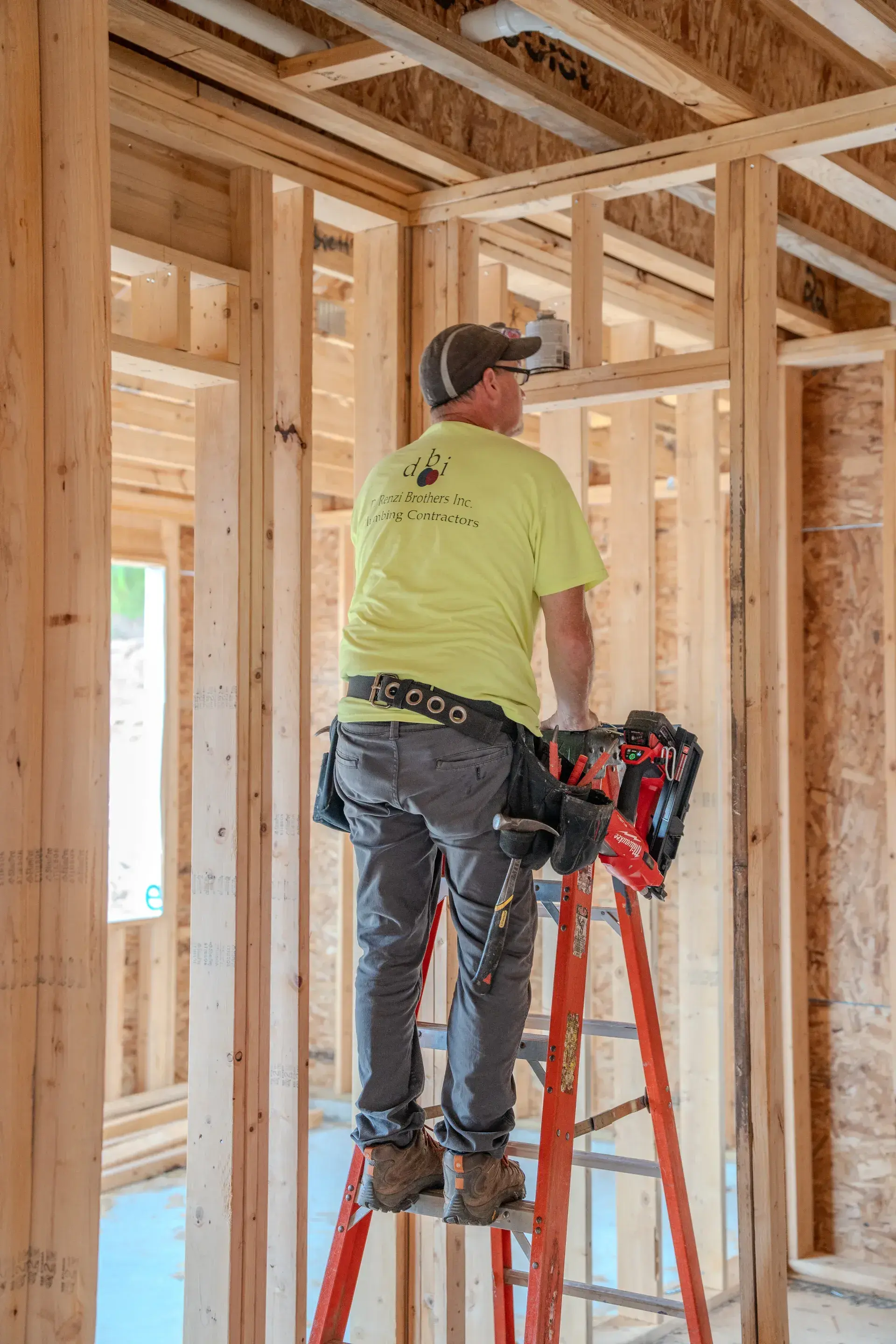 DiRenzi Brothers on a ladder installing a pipe